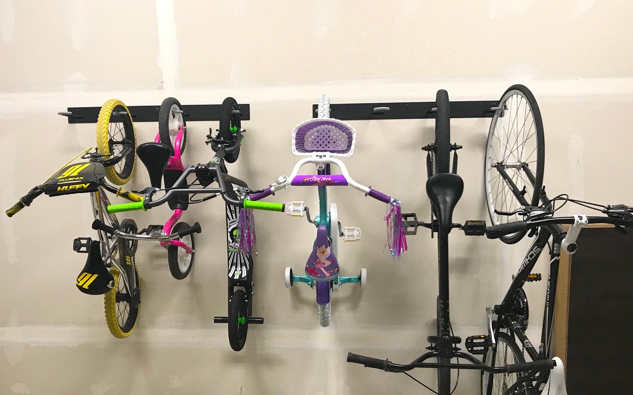 Four bikes hanging from a StoreYourBoard BLAT wall rack in a garage with the floor clear underneath