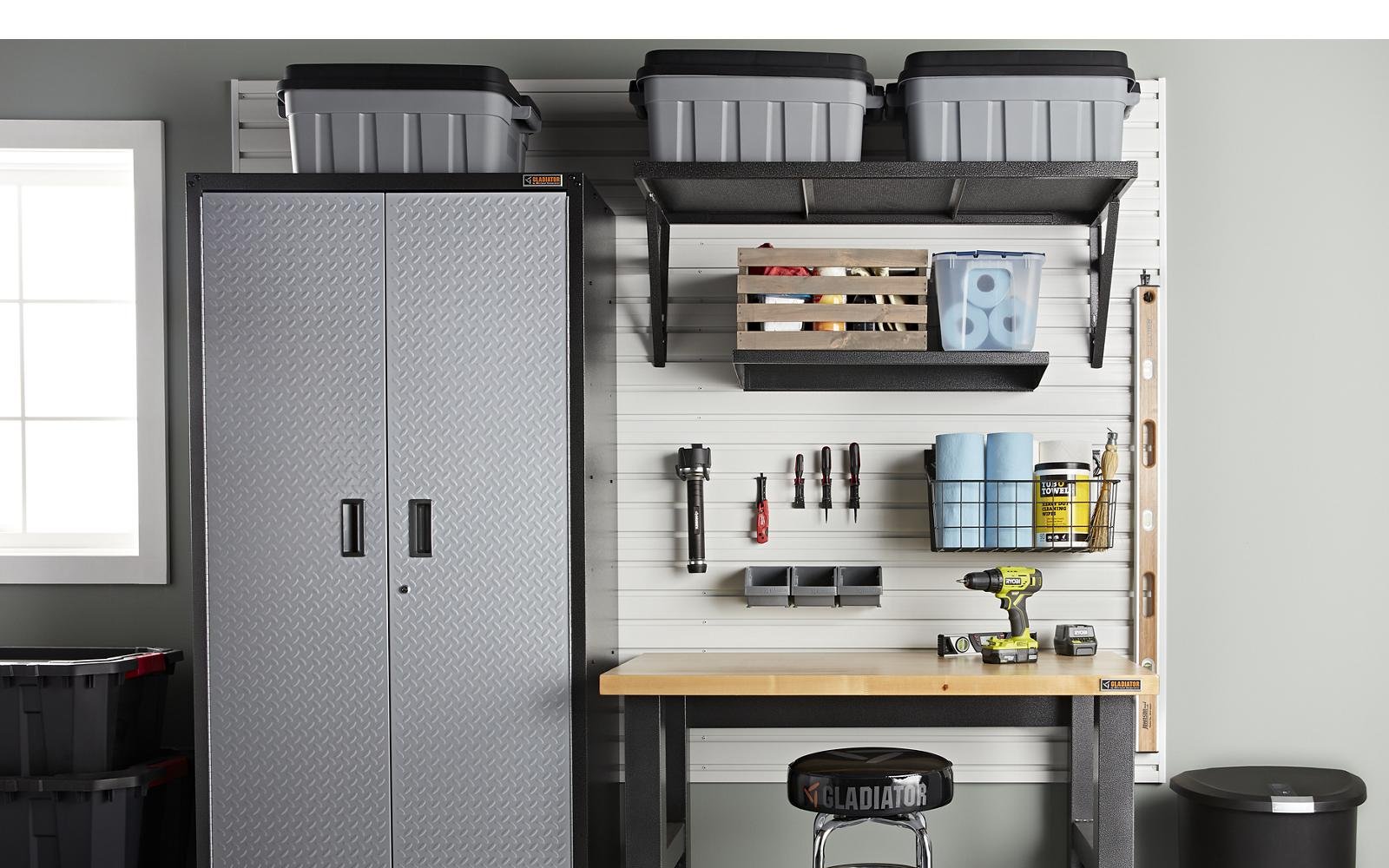 A Gladiator GearBox steel cabinet standing against a finished garage wall beside a bench and a loaded track wall
