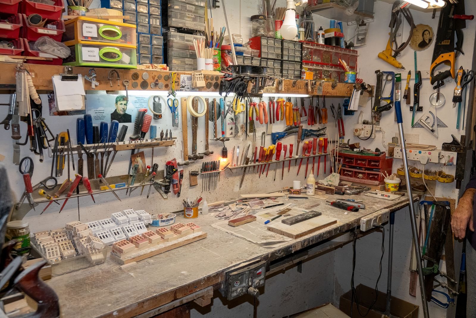An organized garage workshop wall with tools hung in rows above a bench