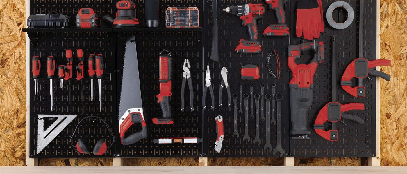 A Wall Control black metal pegboard wall filled with drills, saws, wrenches, clamps and screwdrivers across four panels