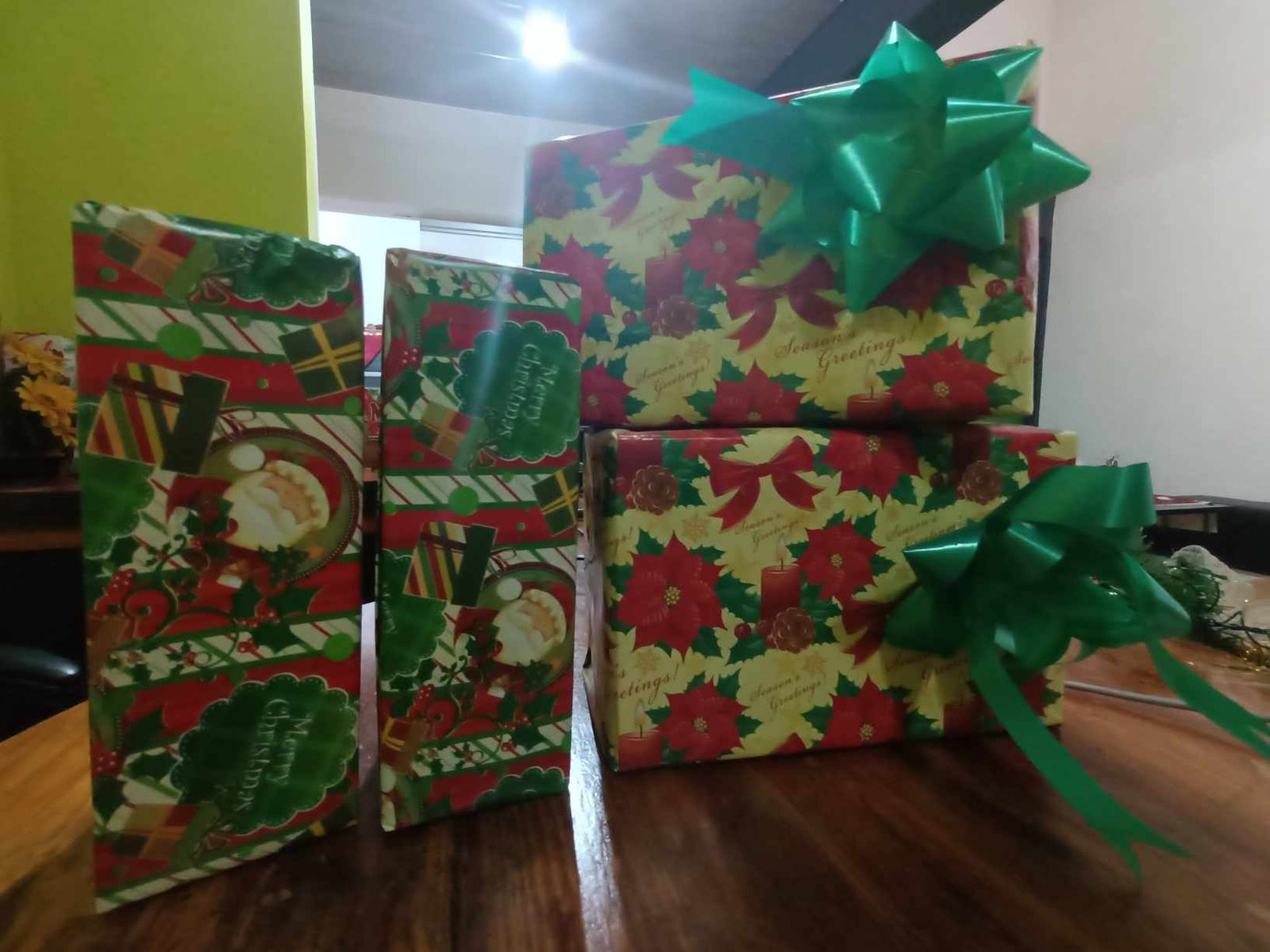 Wrapped presents in colored paper stacked beside a Christmas tree