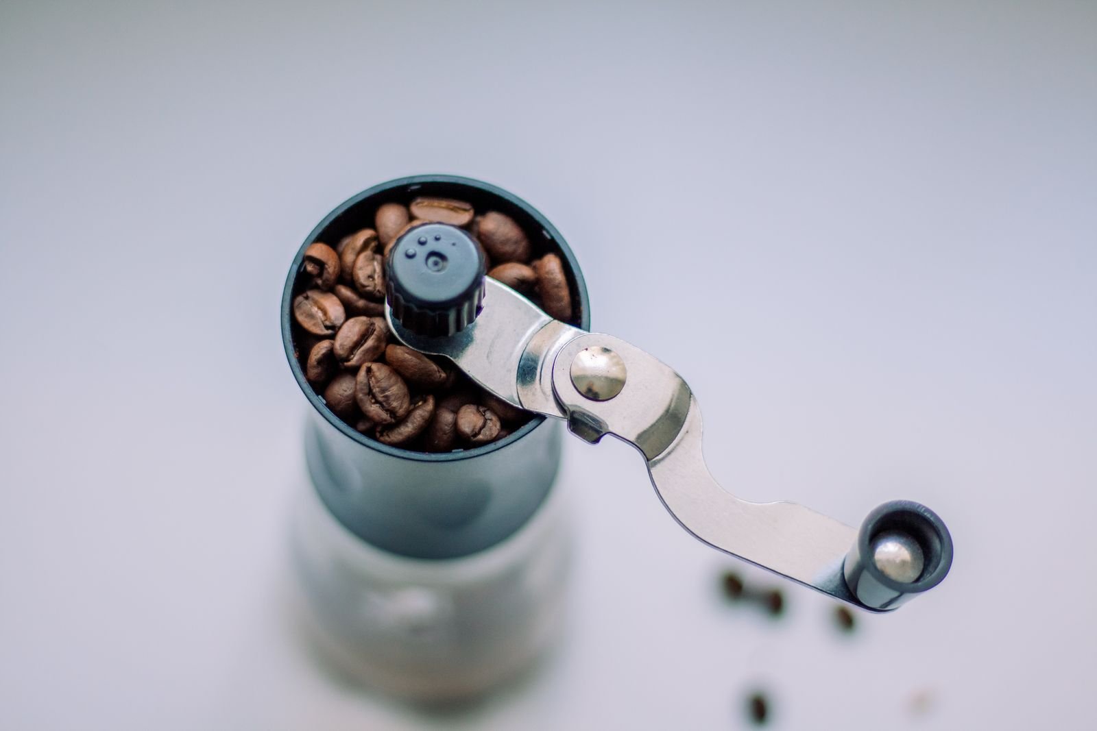 A burr coffee grinder beside a pile of freshly ground coffee on a kitchen counter